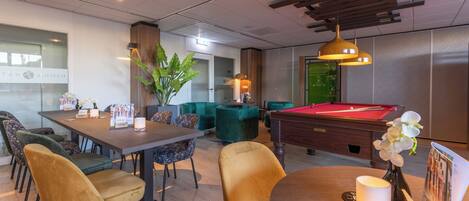 A modern lounge area with a pool table, comfortable seating, and a billiards table.