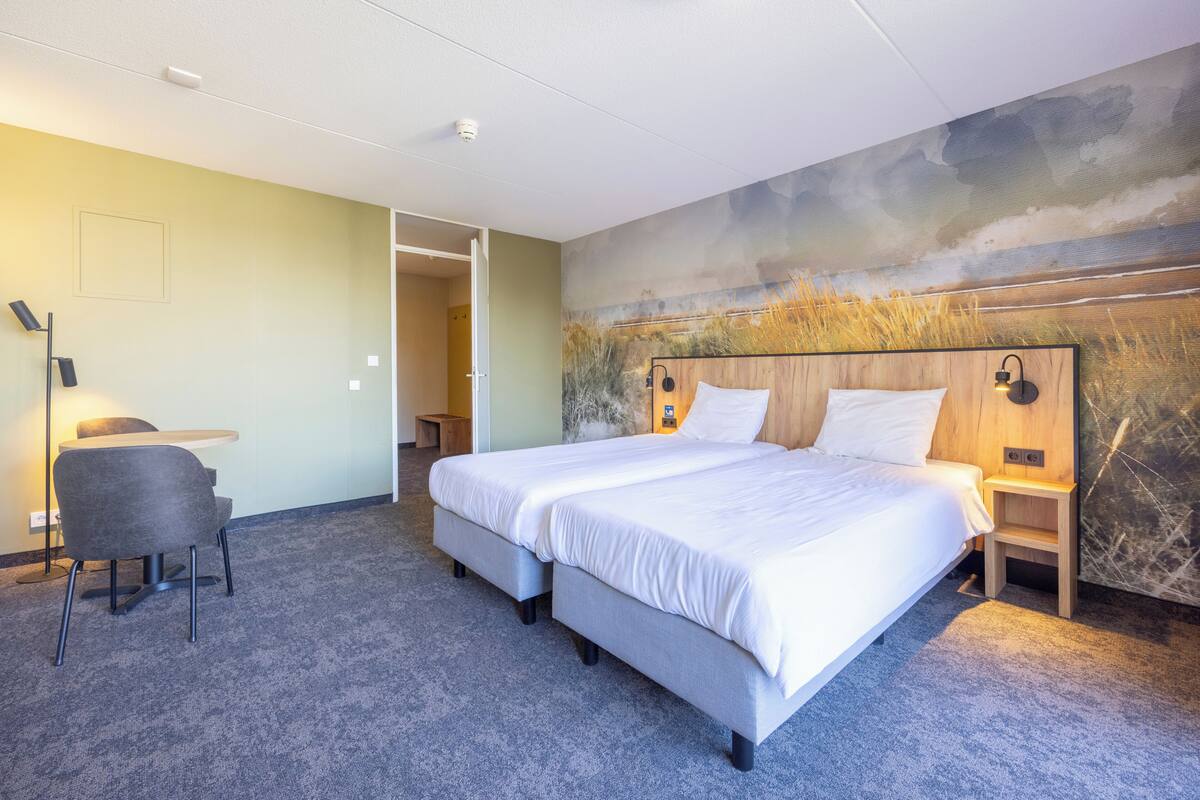 A double bed with a headboard, a desk with a chair, and a small table.