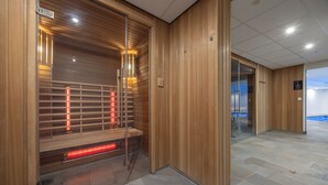 A sauna room with wooden walls, a bench, and red heating elements. - Fletcher Hotel-Restaurant Jan van Scorel (Schoorl)