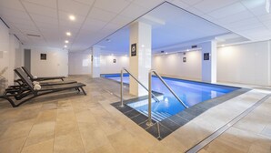 A swimming pool area with a tiled floor, two lounge chairs, and a pool ladder. - Fletcher Hotel-Restaurant Jan van Scorel (Schoorl)