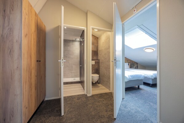 Un dormitorio moderno con tragaluces, vestidor y zona de ducha.