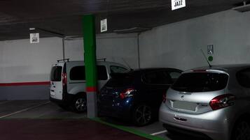 Un aparcamiento con tres coches estacionados en plazas delimitadas por líneas verdes y señales blancas que indican 'abba JAZZ'.