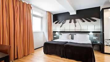 Una habitación de hotel moderna con una cama grande, un cabecero con motivos de piano, un escritorio y una silla.