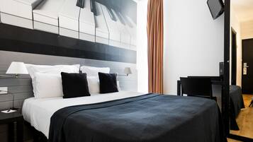 A modern hotel room with a large bed, a desk, and a flat-screen TV.