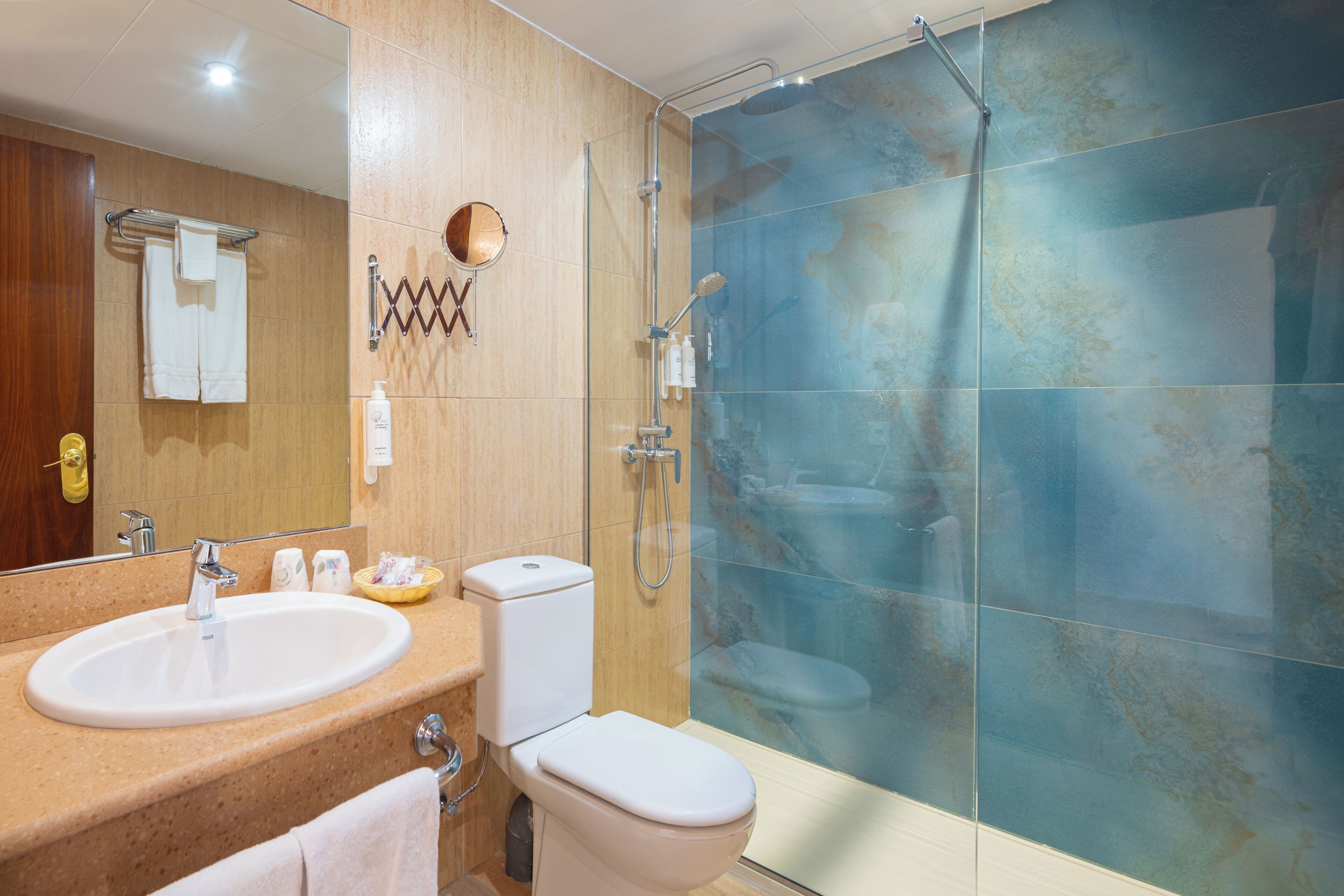 A bathroom with a sink, toilet, and glass shower enclosure.