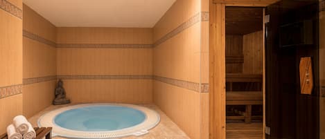 Un cuarto de spa con un jacuzzi, bancos de madera y una estatua.