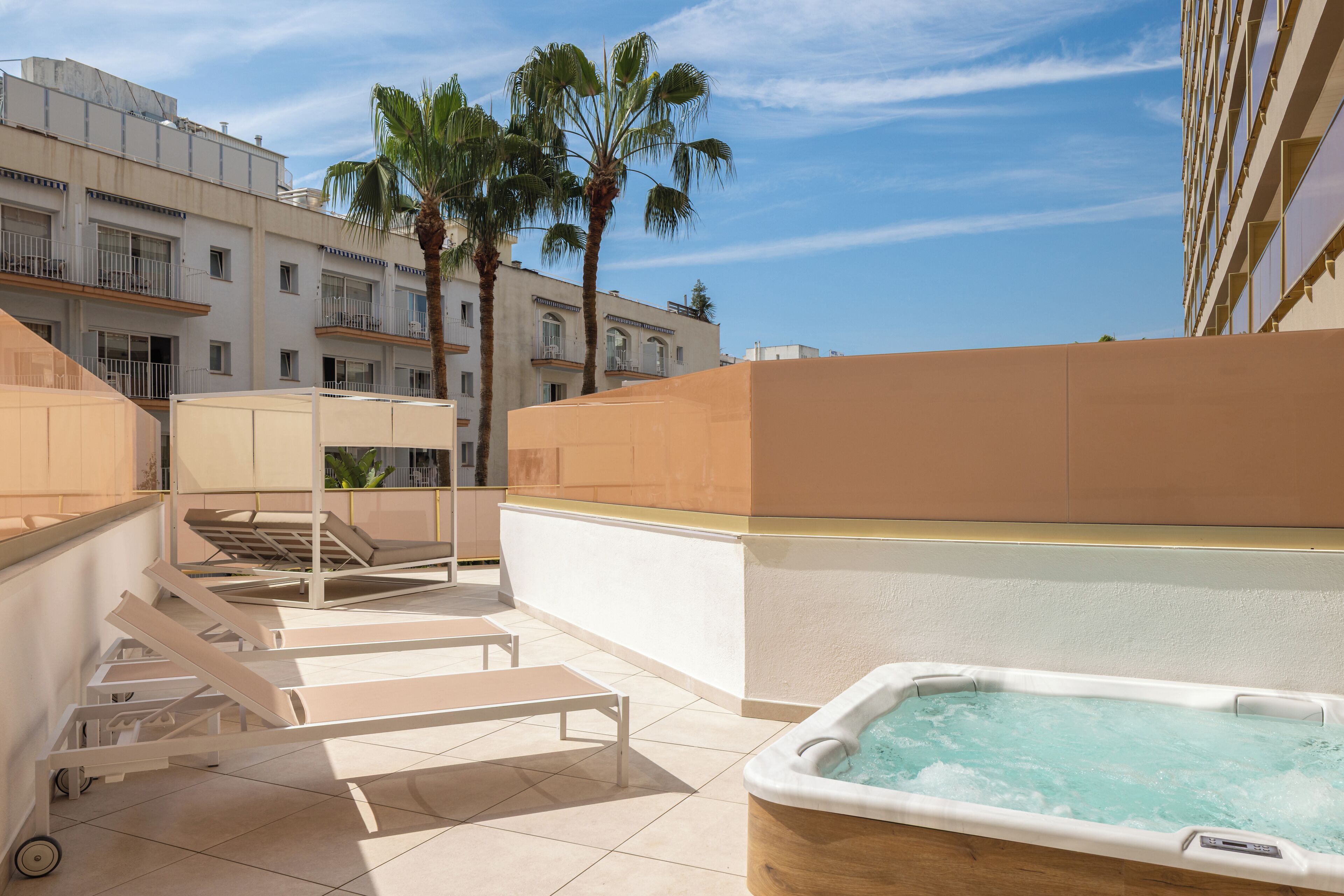 Terraza en la azotea con jacuzzi, sillas de descanso y palmeras.
