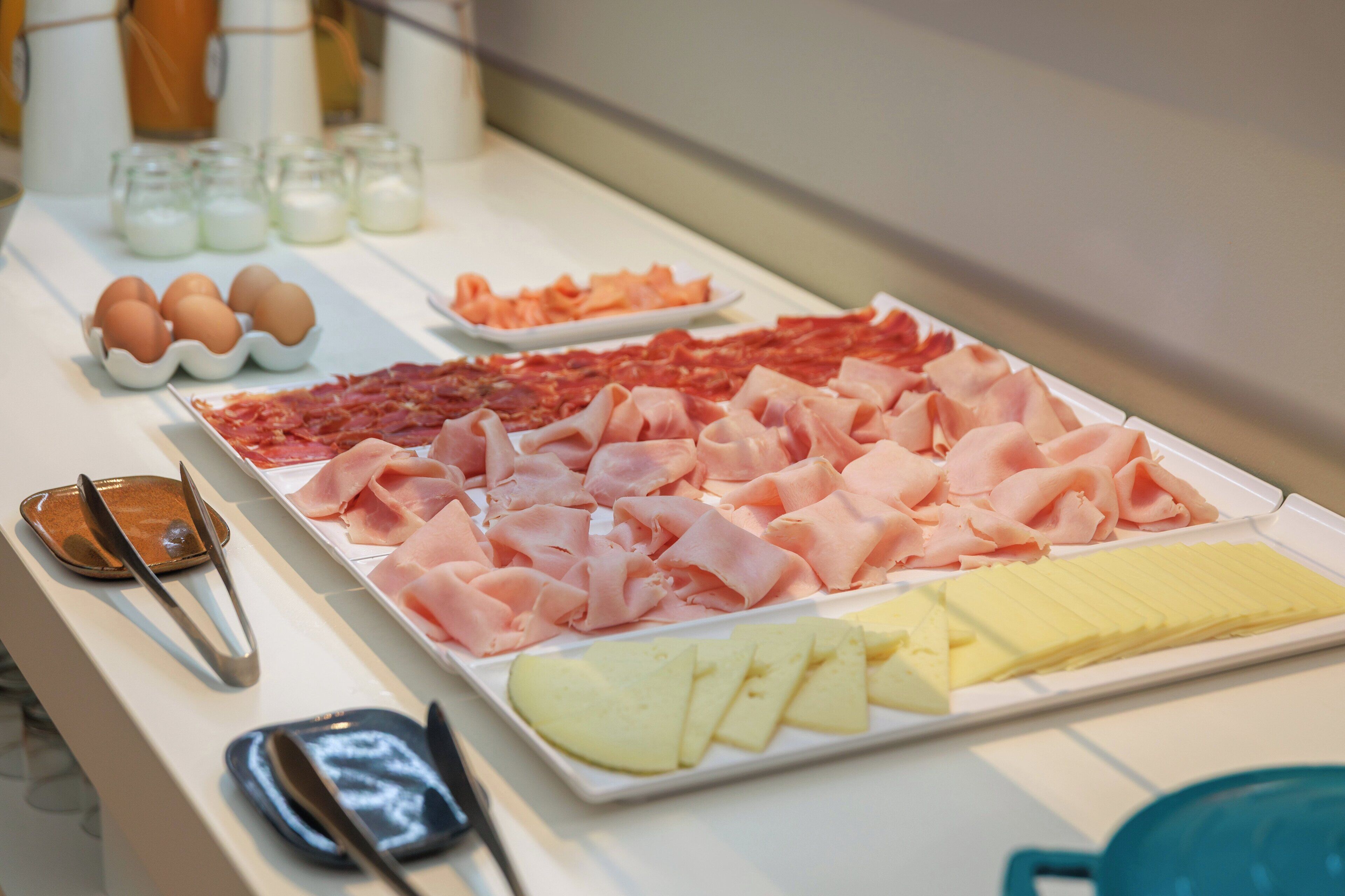 A buffet with various food items including meats, cheeses, and fruits.