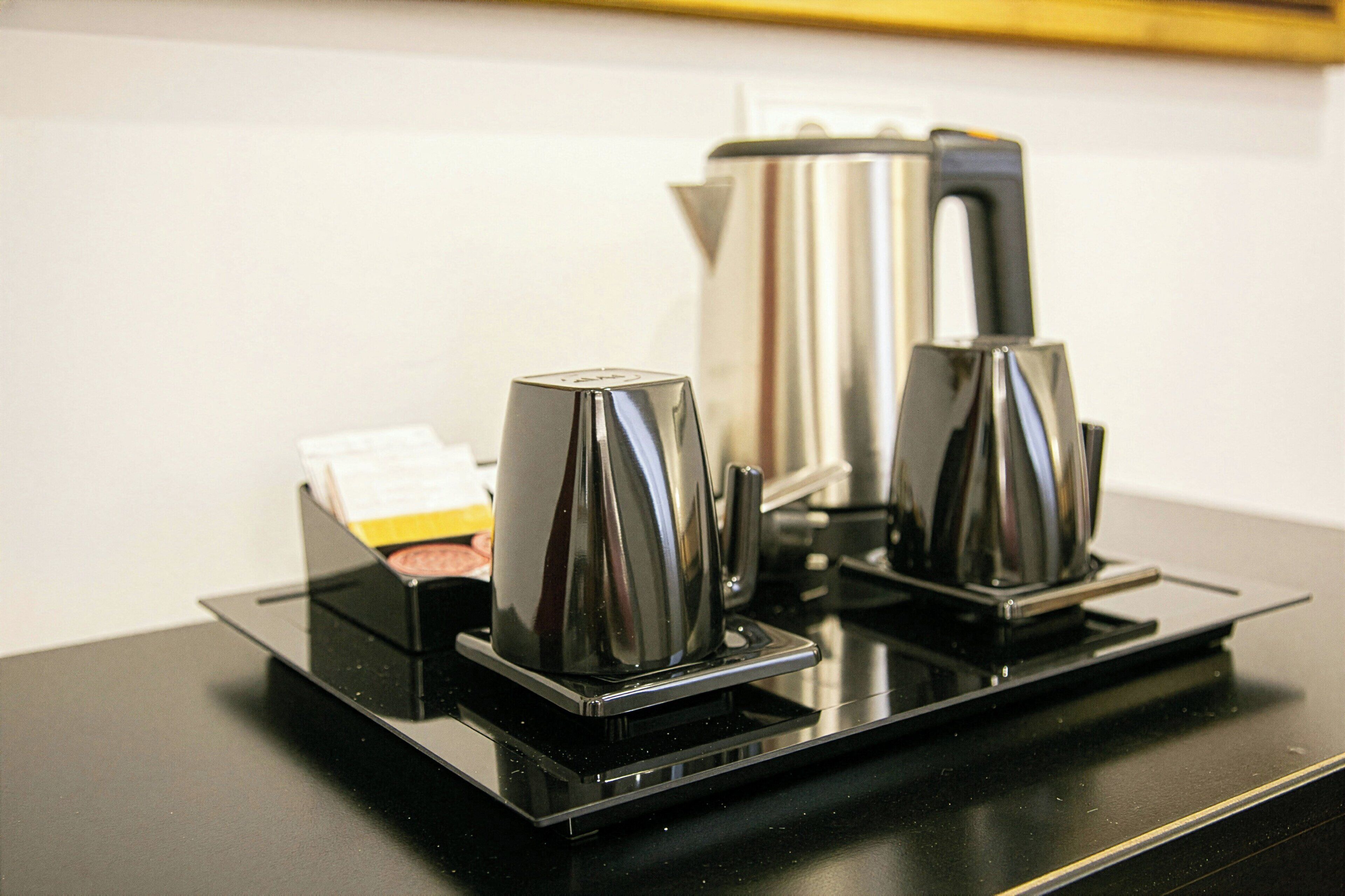 Una cafetera y un hervidor sobre una encimera negra.
