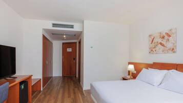 Una habitación de hotel con cama, televisión, escritorio y armario.