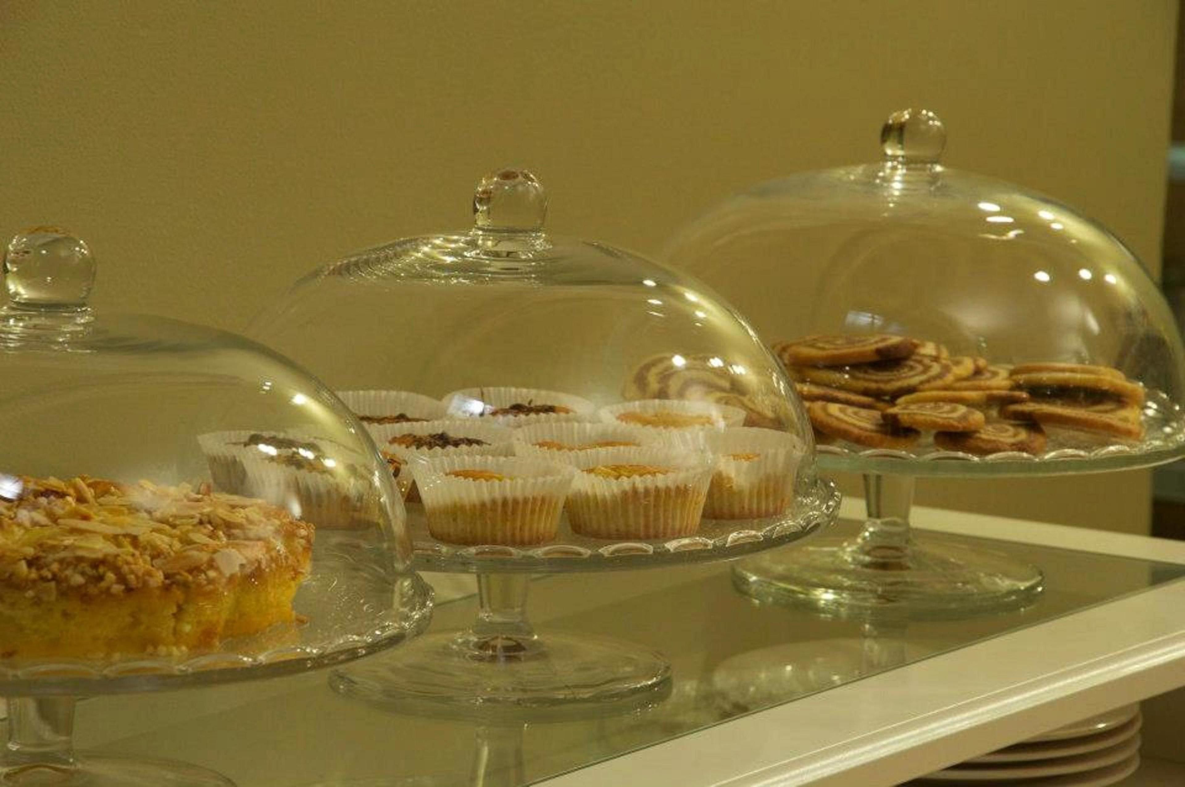 Un bufé con diversos postres bajo campanas de cristal.