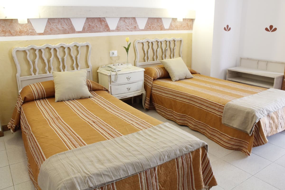 Une chambre d’hôtel avec deux lits, chacun doté de draps à rayures et d’une table de chevet.
