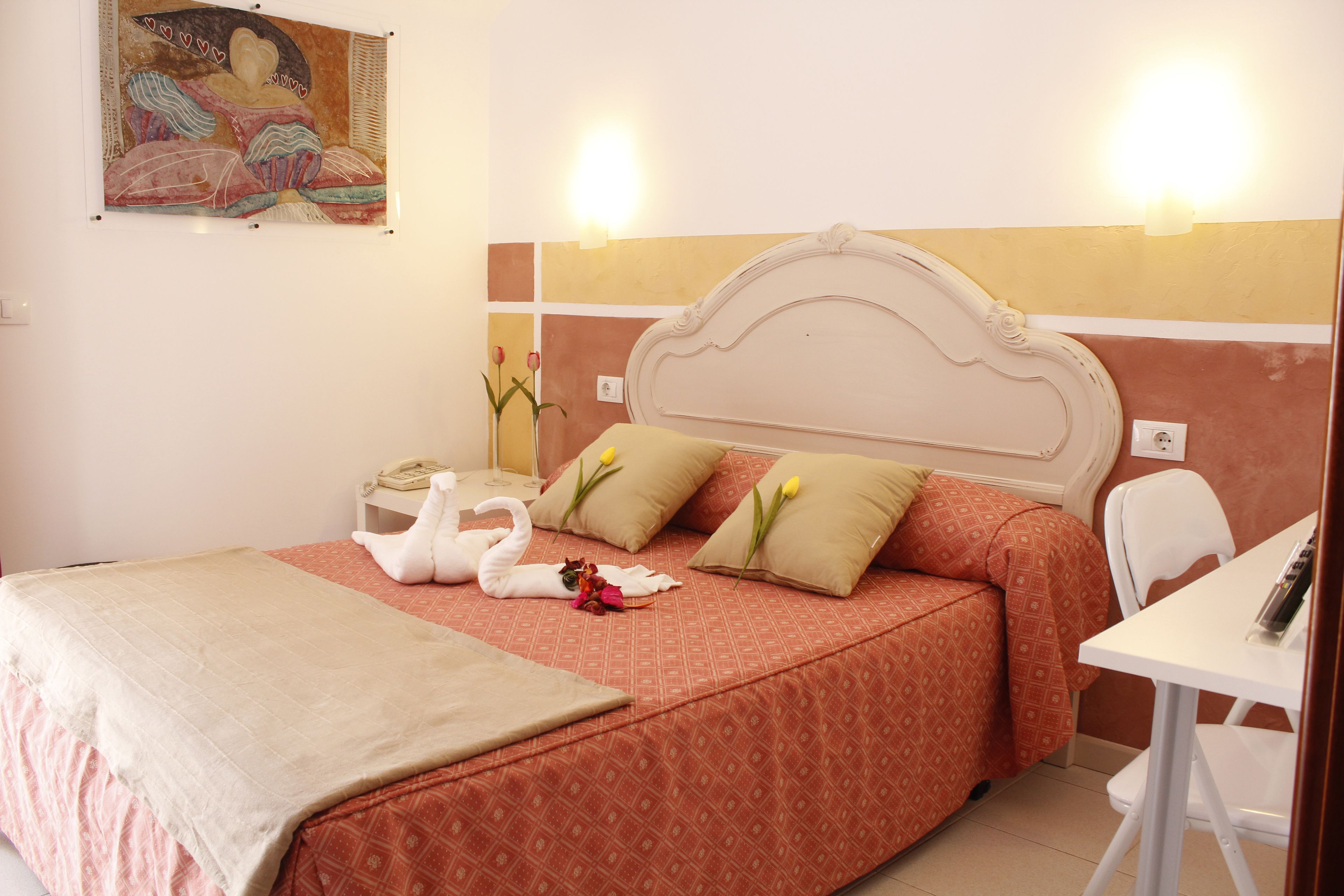 Una camera d'albergo con un letto, un comodino e una sedia.