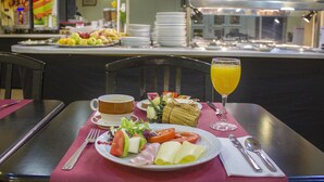 Een ontbijtsetting met een bord eten, een glas sinaasappelsap en een kop koffie op een tafel.