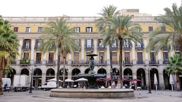 A courtyard with a fountain, palm trees, and a building with balconies and arches.