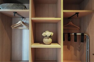 Un armario de madera con varios estantes, una barra para colgar ropa y un pequeño jarrón con flores.