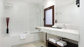 Uma casa de banho moderna com cabine de duche em vidro, lavatório branco com espelho e porta-toalhas.