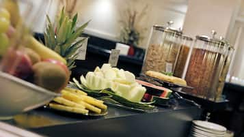 Un buffet proposant une variété d’aliments, notamment des fruits, du fromage et un gâteau.