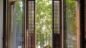 A window with a view of trees and a street. - Arc la Rambla (Barcelona)