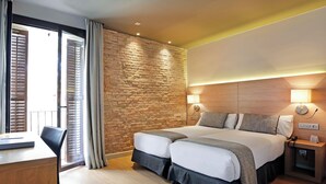 A hotel room with a large bed, a desk, and a stone wall. - Arc la Rambla (Barcelona)