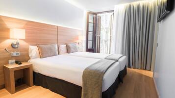 Et hotelværelse med en stor seng, sengeborde, en lampe og udsigt til det fri.