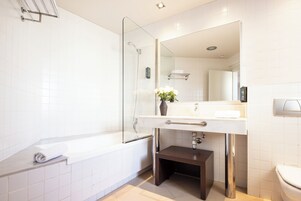 A modern bathroom with a glass shower enclosure, a white sink with a dark countertop, and a toilet.