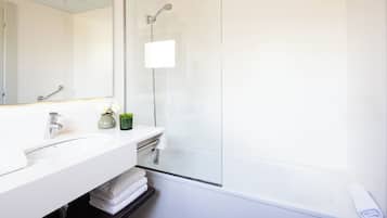 Un bagno moderno con un mobile lavabo bianco, una cabina doccia in vetro e un grande specchio.