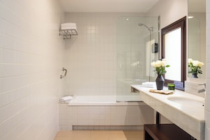 Une salle de bain moderne avec une douche à l’italienne en verre, une baignoire blanche et un meuble-lavabo avec un miroir.
