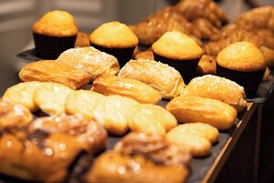 A variety of pastries including muffins and danishes, some dusted with powdered sugar.