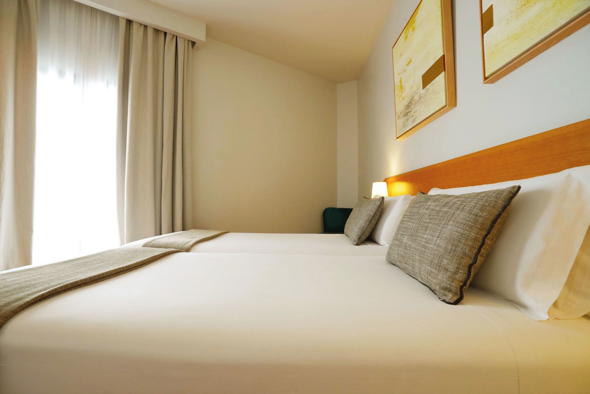 A hotel room with a large bed, a nightstand, a lamp, and two framed pictures on the wall.