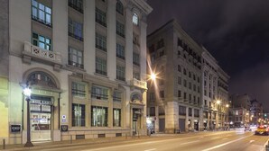 Um edifício histórico com uma entrada imponente, vários andares e localização destacada na esquina.