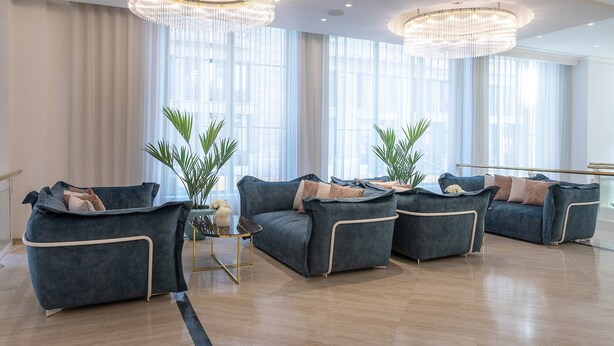 Uma sala de estar espaçosa com design moderno, com um lustre grande, assentos confortáveis e janelas amplas.