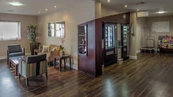 A hotel lobby with a reception desk, seating area, and vending machines.