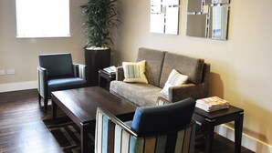 A living room with a sofa, armchairs, a coffee table, and a potted plant. - Holiday Inn Express London-Royal Docks, Docklands by IHG (London)