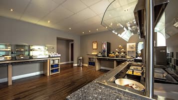 A modern kitchen with granite countertops, stainless steel appliances, and a glass partition.