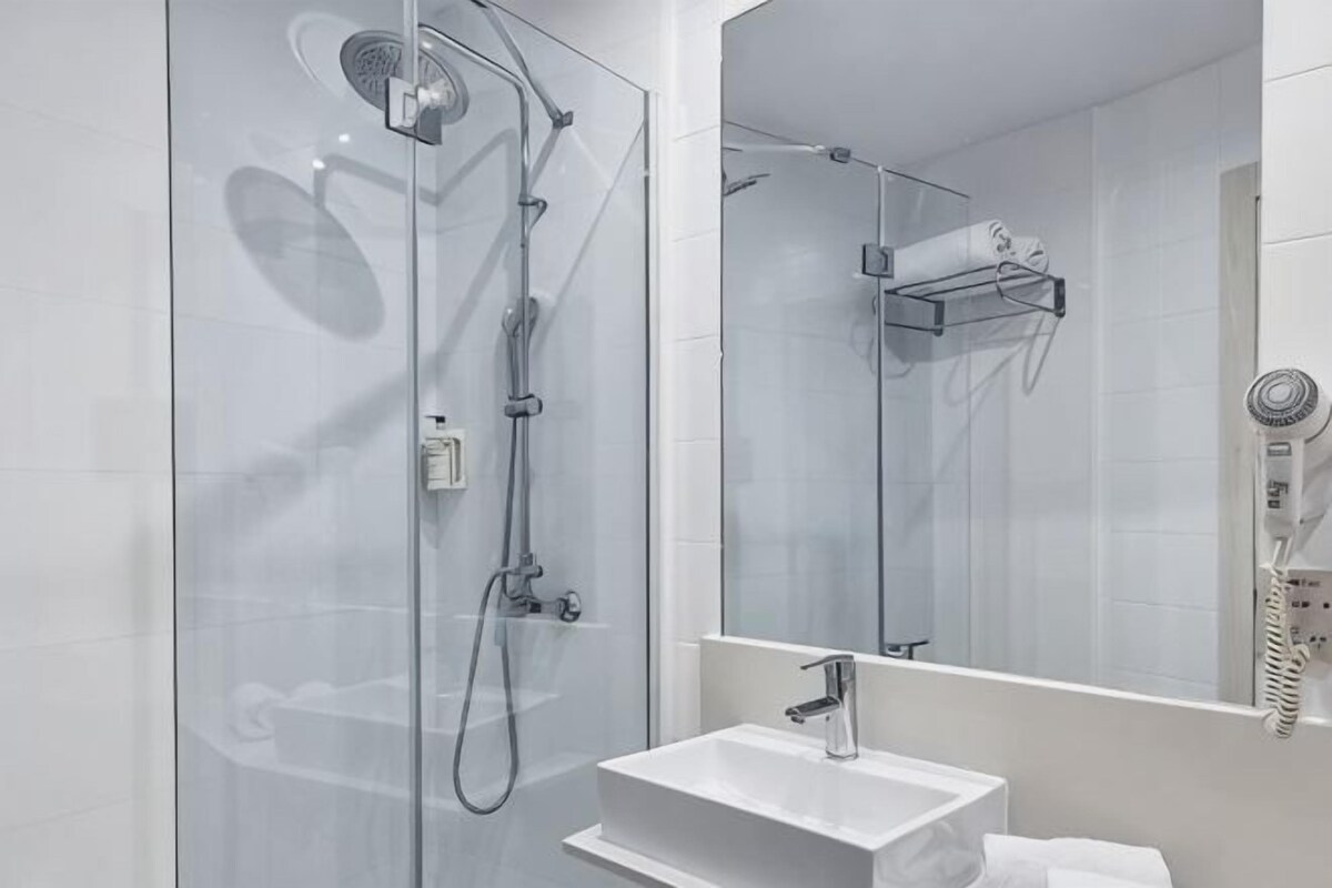 A modern bathroom with a glass-enclosed shower, a white sink, and a mirror.