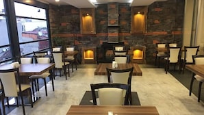 Um restaurante com paredes de pedra, mesas e cadeiras de madeira.