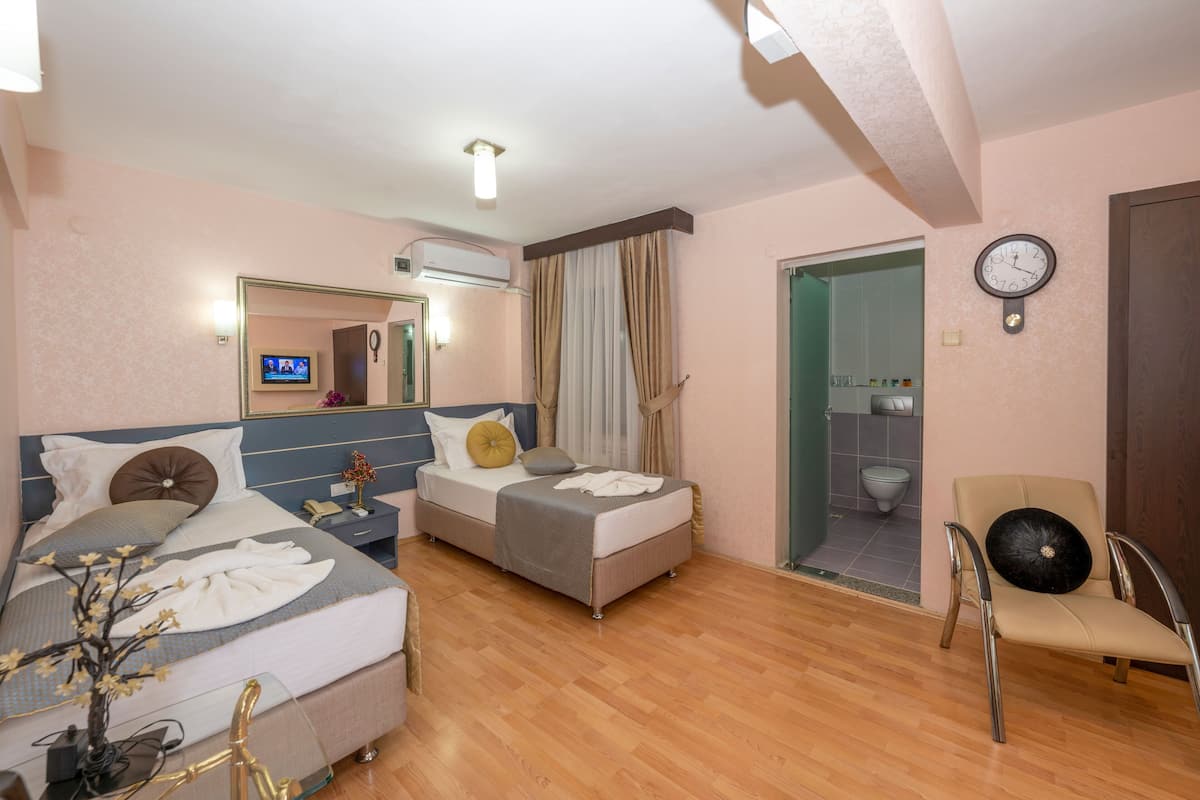 A hotel room with two beds, a chair, a TV, and a bathroom visible through an open door.