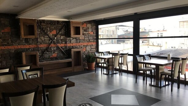 Um restaurante moderno com parede de pedra e lareira de tijolos, janelas amplas e chão ladrilhado.