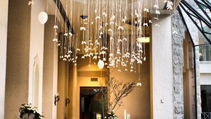 A spacious lobby with a high ceiling decorated with hanging spherical ornaments and strings of lights, a marble floor, and a staircase to the right. - Jacir Palace Hotel Bethlehem (Bethlehem)
