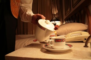 A person pouring tea into a cup on a table with a telephone and a pillow in the background. - Jacir Palace Hotel Bethlehem (Bethlehem)