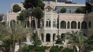 A historic building with multiple arches and a central courtyard with palm trees. - Jacir Palace Hotel Bethlehem (Bethlehem)