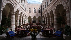 A spacious atrium with high ceilings, arched columns, and a central fountain. Tables and chairs are arranged for dining. - Jacir Palace Hotel Bethlehem (Bethlehem)