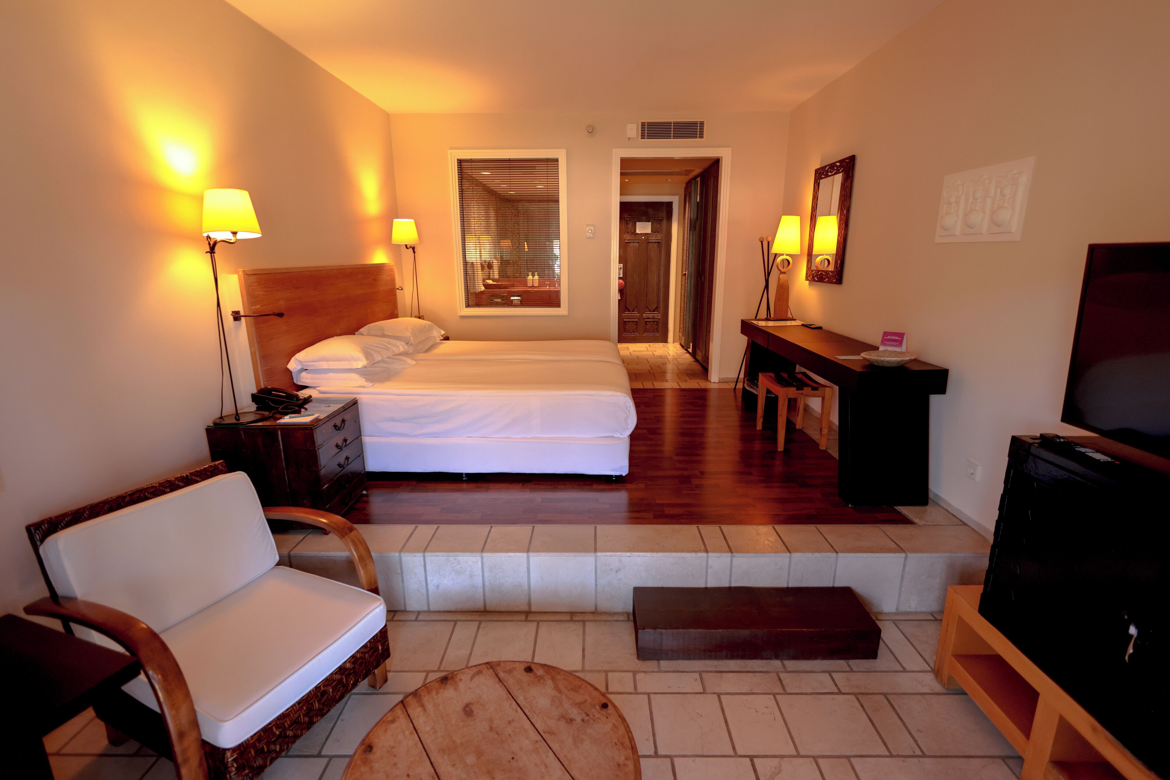 A hotel room with a bed, a sofa, a TV, a desk, and a mirror.