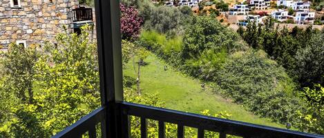 A stone building with a balcony overlooking a hillside with white houses and lush greenery.