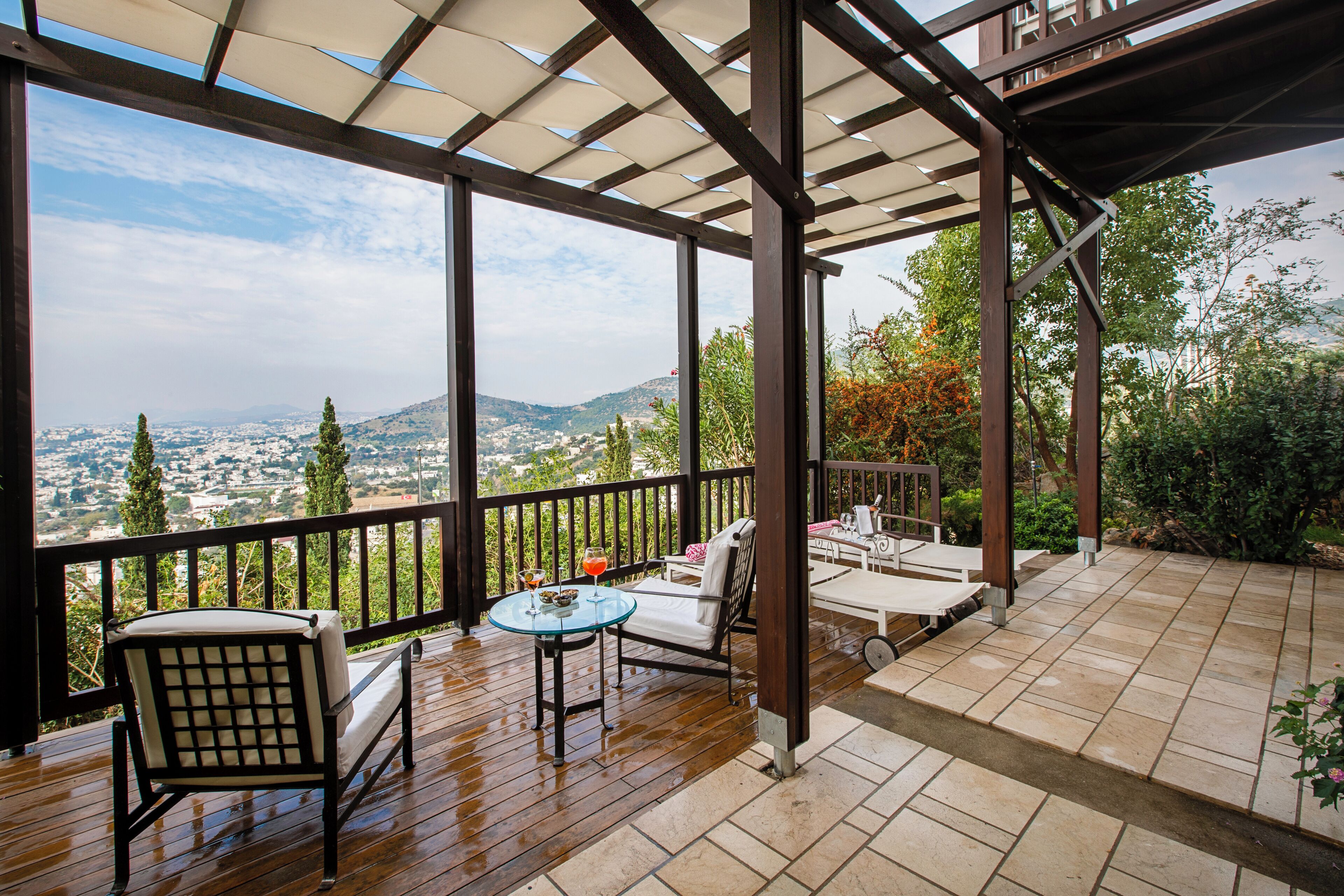 Une terrasse extérieure couverte offrant une vue sur la ville et les collines.