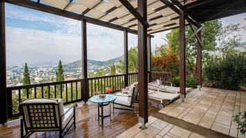 A covered outdoor patio with a view of the city and hills.