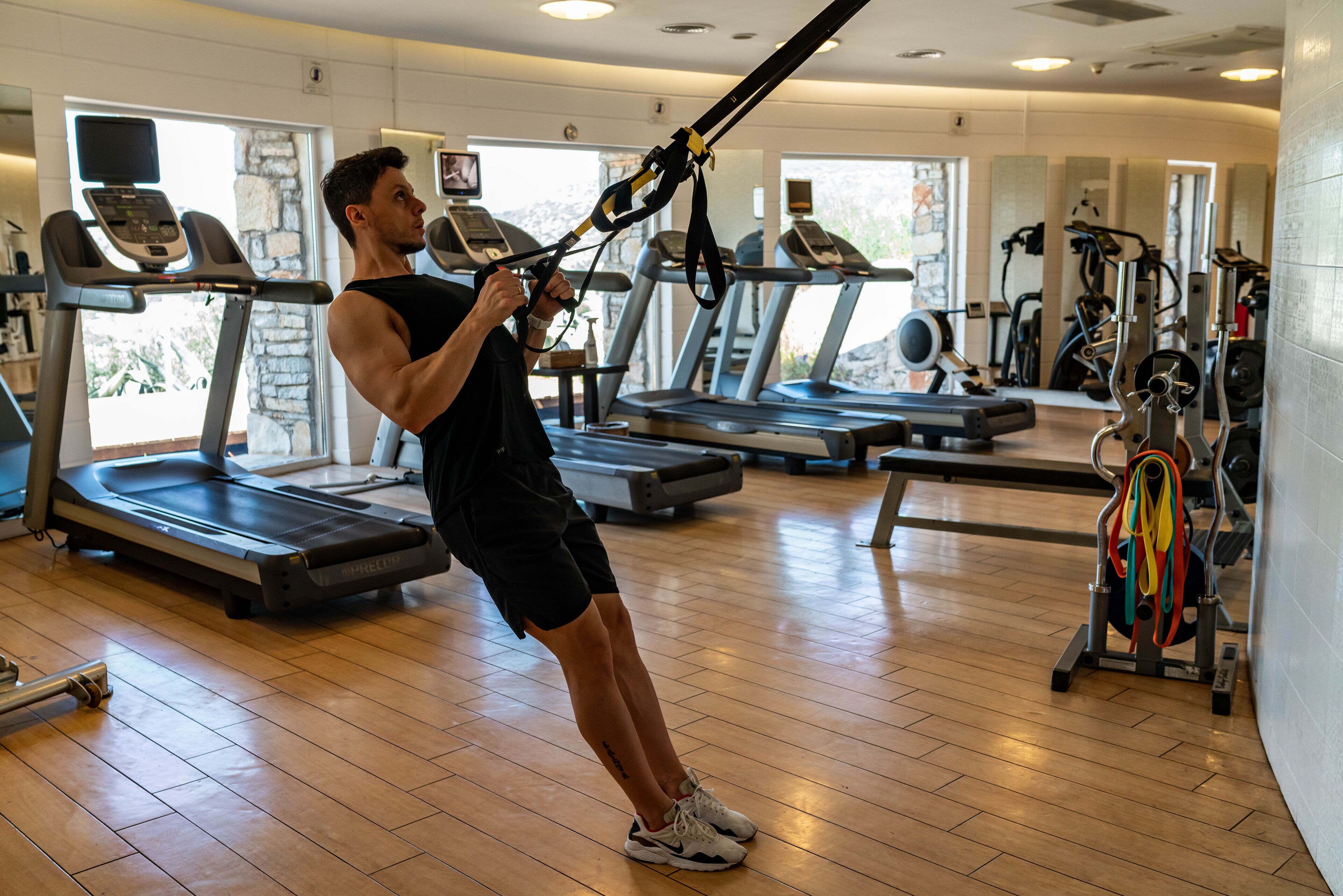 Et fitnesscenter med løbebånd, træningsudstyr og trægulv.
