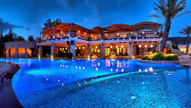 Ein luxuriöses Hotel mit großem Schwimmbecken, Steinarchitektur und Außenbereichen zum Sitzen.