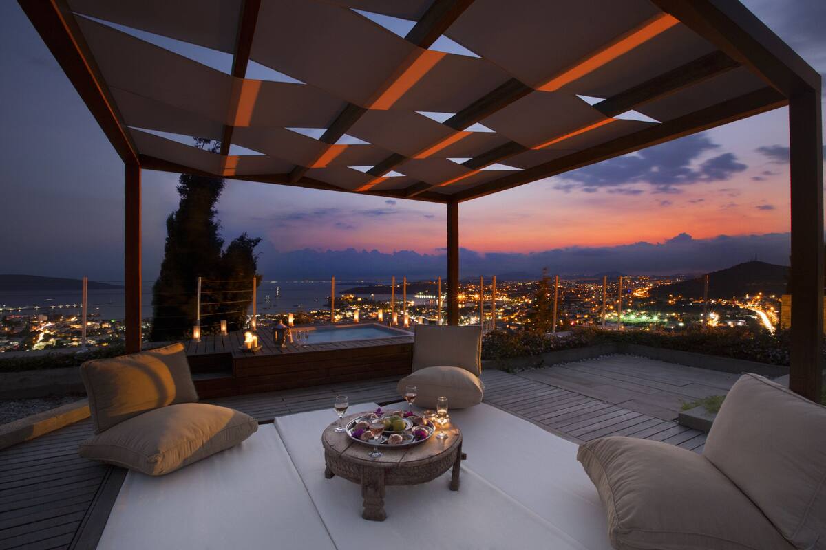 A rooftop terrace with a hot tub, lounge chairs, and a table set for dining.
